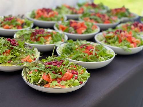Bowls of mixed field green salads with pomegranate pearls, tomato and cucumber