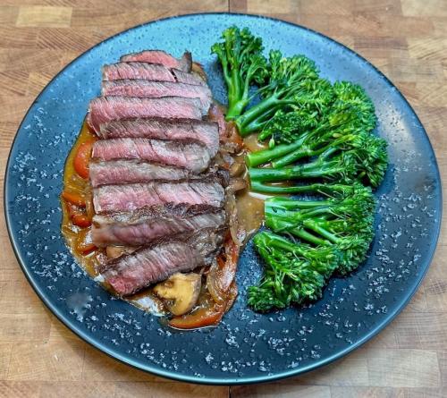 Sliced and plated British Wagyu strip sirloin with tender stem broccoli.