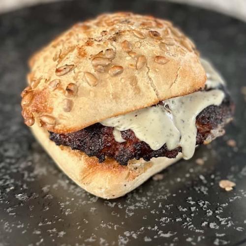 Minted lamb burger topped with melted Camembert on a toasted bun