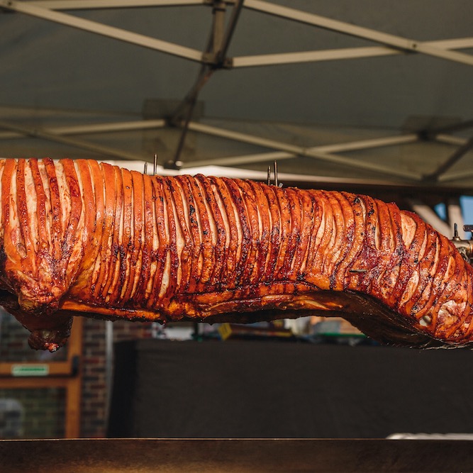Hog roast with golden crackling after it has been raised out of the hog roast machine